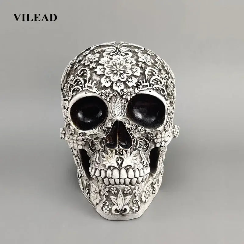 Silver skull figurine with intricate floral leaf patterns black eye sockets and toothed grin decorbites 20cm carved skull