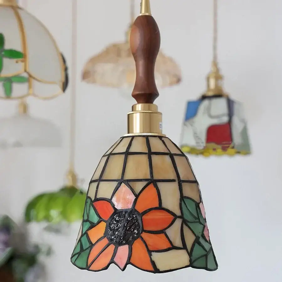 A vibrant orange and green floral stained glass pendant light with wooden handle and brass fittings for decorbites colorful glass led
