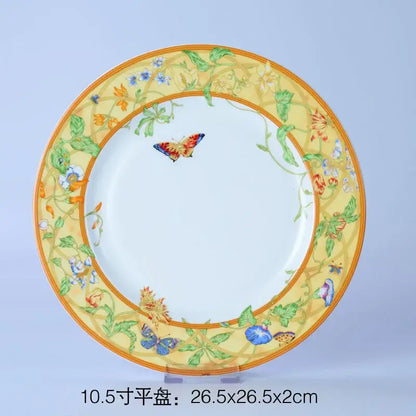 A decorative bone dinnerware set plate with yellow border green vines blue orange flowers and a colorful butterfly design