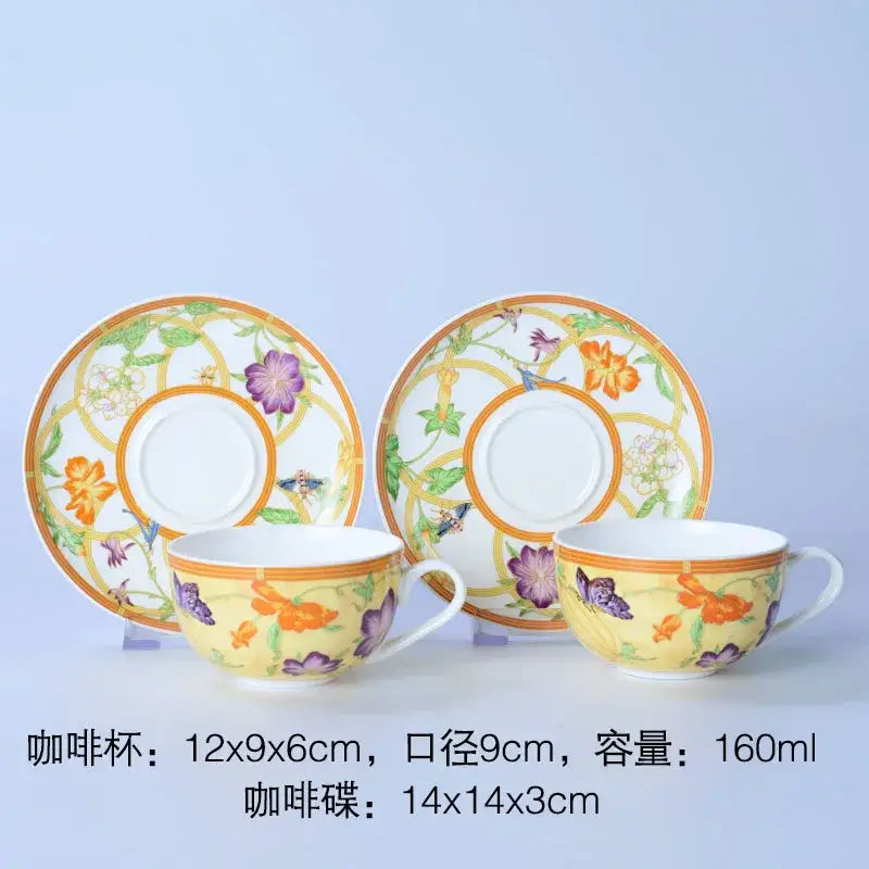 A pair of elegant yellow ceramic coffee cups with floral butterfly patterns and gold border in bone dinnerware set