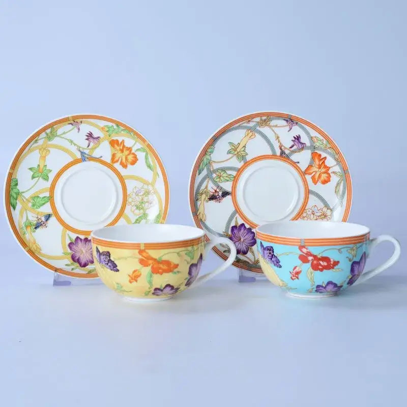 Two ornate porcelain teacups with vibrant floral butterfly patterns and gold trim in a floral turquoise bone dinnerware set