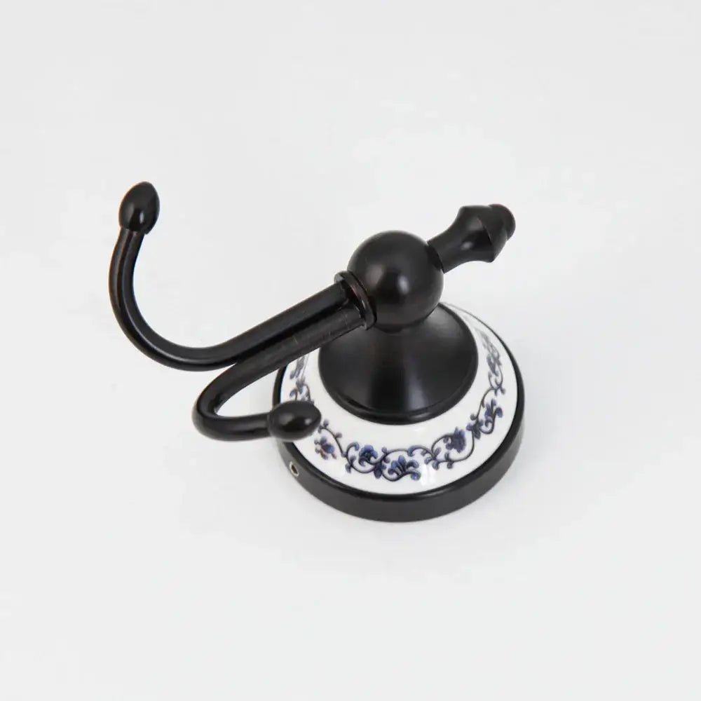 Black stainless steel double robe hook with white ceramic base and blue floral decorbites stainless steel bathroom hook