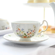 A delicate white bone china tea cup with gold rim and vibrant floral pattern in a floral tea cup set