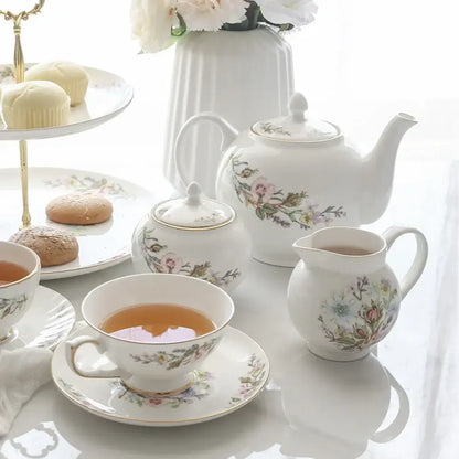 White bone china tea set featuring a white porcelain teapot with floral patterns and gold-trimmed lid for tea-drinking experience
