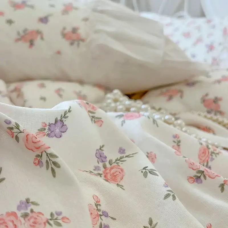 Cream-colored cotton bedding set with pleat lace ruffles featuring soft pink and purple floral pattern and green leaves