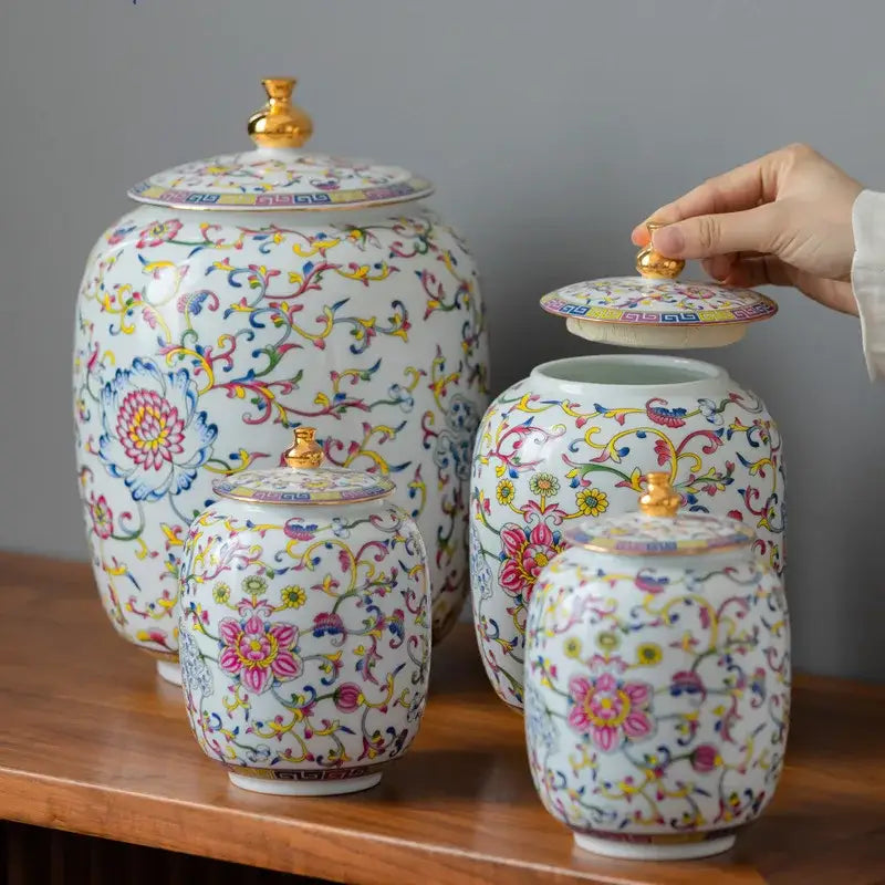 Set of four floral white enamelled porcelain tea caddy ginger jars with vibrant blooms and gold-accented lids