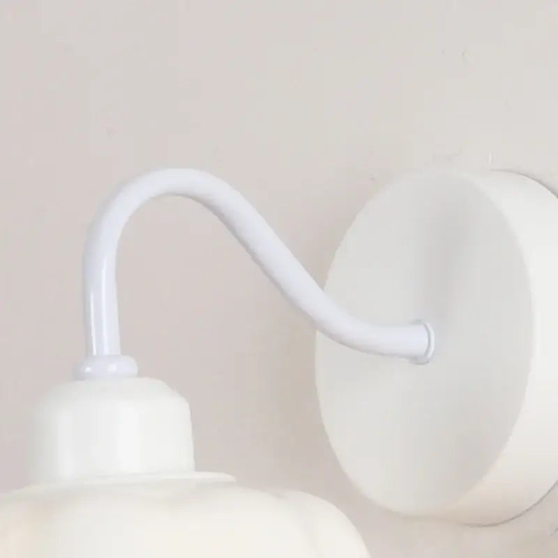 Floral white glass wall sconce with white metal curved arm and pull chain switch for stair lighting