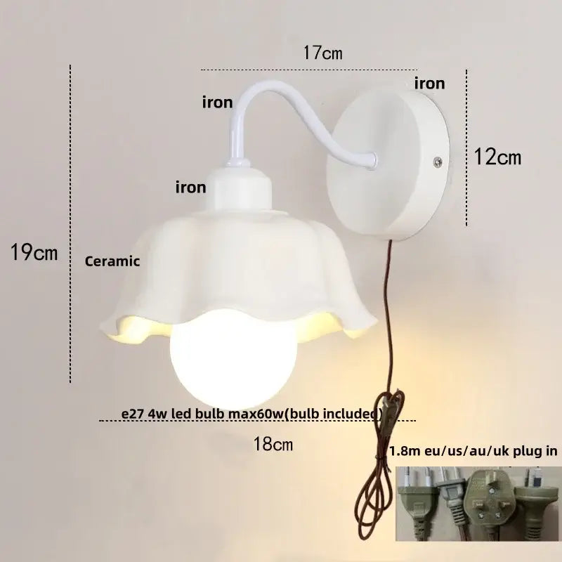 Floral white glass wall sconce with pull chain switch featuring white ceramic lamp and curved iron arm wall mount