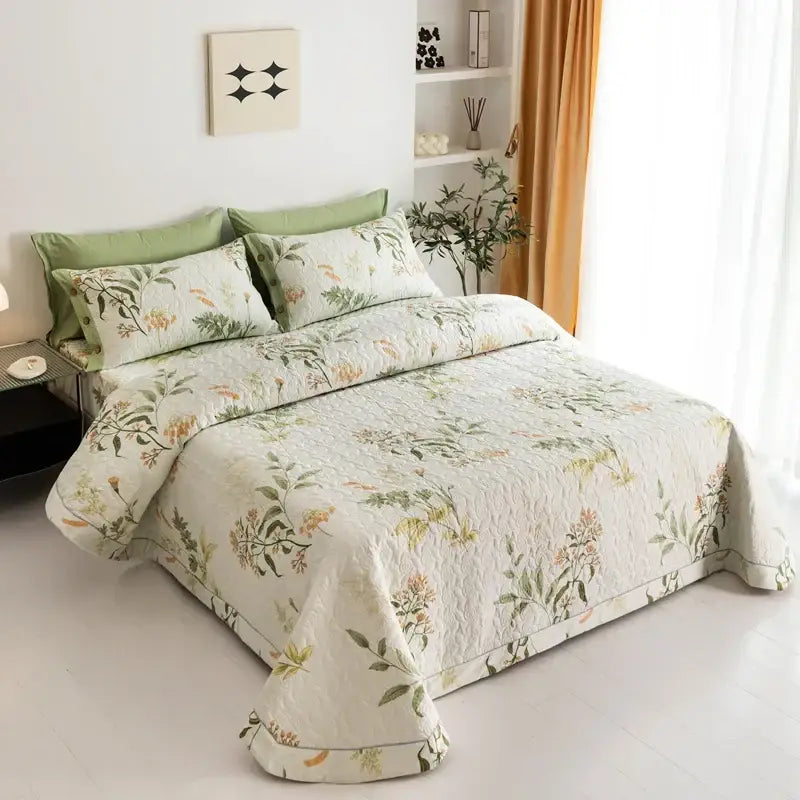 A cream-colored cotton quilted bed cover set with a delicate floral print in muted greens and golds