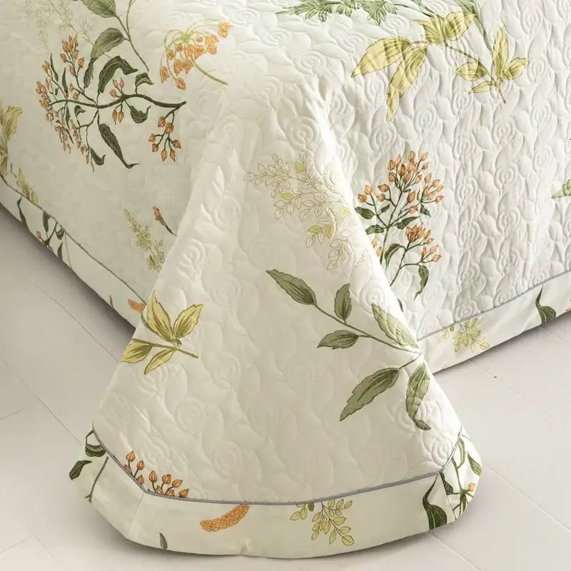 Cream-colored cotton quilted bed cover set with embroidered green leaves and orange blossoms, subtle gray border
