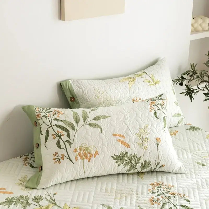 White quilted cotton pillow sham with green and orange floral embroidery and sage-green piping in bed cover set