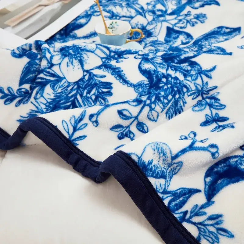 White fleece cozy flannel plush blanket with blue floral pattern and navy trim for decorbites cozy flannel decor