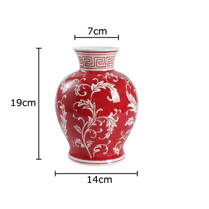 A glossy red porcelain vase with intricate white floral patterns and a greek key design for living room decor