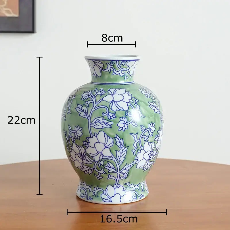 Green ceramic vase with white porcelain floral patterns featuring rounded body and narrow neck for living room decor