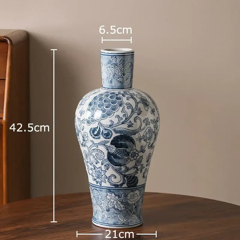 A tall slender white porcelain vase with intricate blue and white floral patterns and a central bird motif for living room decor