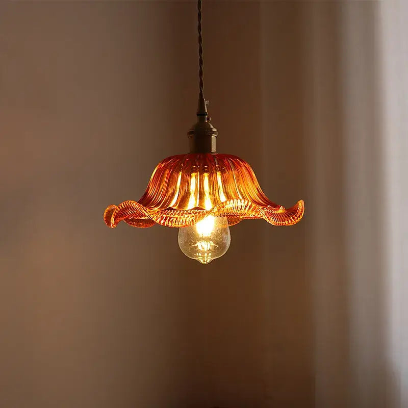 A warm amber glass pendant light with fluted petal design and visible bulb for decorbites green stripe glass fixture