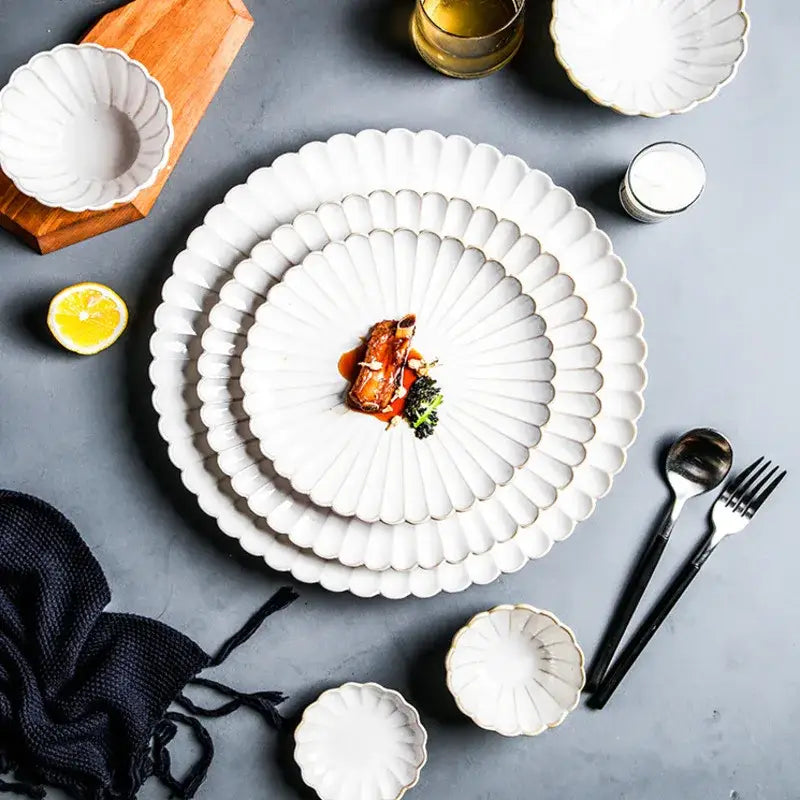 Stacked white ceramic plates with scalloped fan edge in a fluted petal white ceramic dinnerware set with gold trim decorbites ceramic white glaze