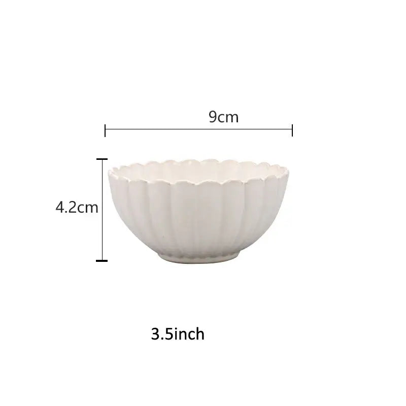 A white ceramic bowl with a scalloped rim and ceramic white glaze from decorbites dinnerware set with gold trim