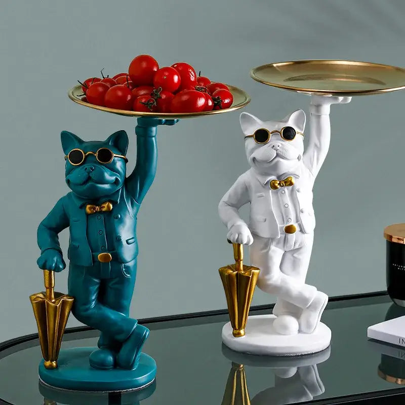 Two stylish teal and white bulldog resin statues with gold accents and sunglasses on a formal black and white statue tray