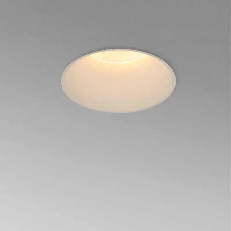 A frameless white decorbites cob led downlight with frosted glass diffuser emitting warm ambient living room light