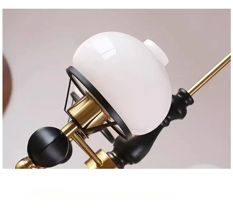 White opaline glass globe suspended from brass and black wrought iron arm in french bauhaus ceiling chandelier decorbites