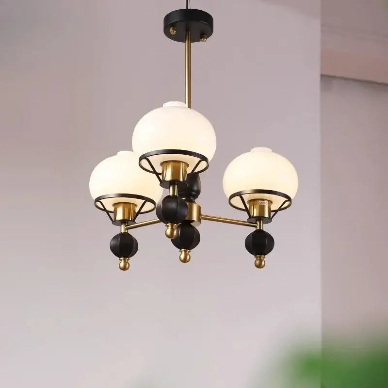 A modern french bauhaus ceiling chandelier with frosted glass globes and brass black metal frame by decorbites