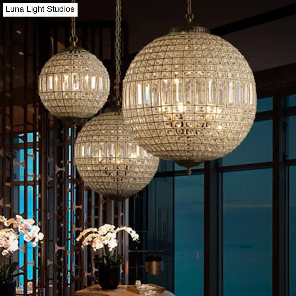 Three globe pendant crystal shade chandeliers with gold-toned brass frames hang from chains in a French country style