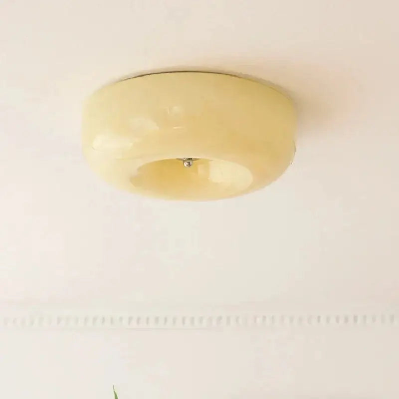 Cream-colored glossy circular ceiling lamp with smooth rounded design for warm and white bedroom lighting decorbites french cream