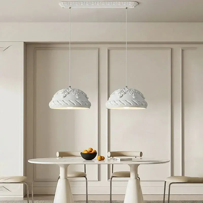 Two elegant french cream style led pendant lights with ornate domes hang above a minimalist dining table decorbites french cream