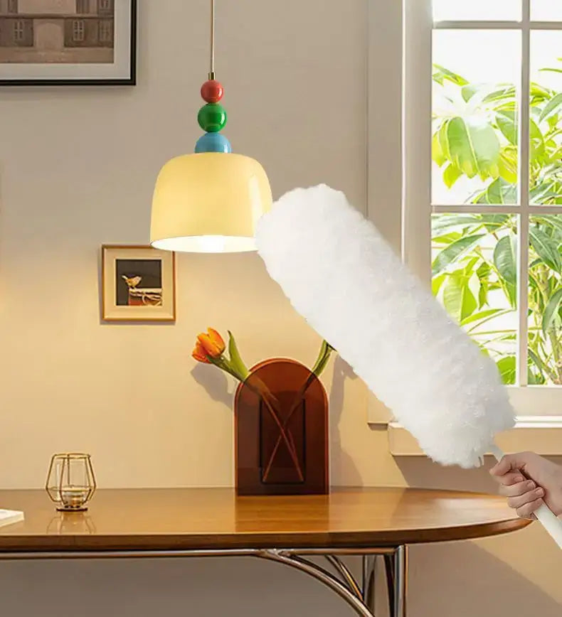 Hand holding white feather duster with long handle near cream style chandelier from decorbites french cream collection