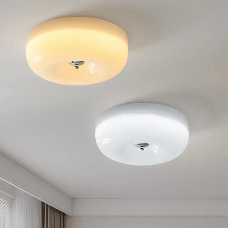 Two french cream ceiling lamps with frosted glass and metallic fixtures emitting warm yellow and white light