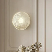 A cream-colored French cream wind sunburst wall lamp with frosted glass diffuser and metallic accents for bedroom decorbites
