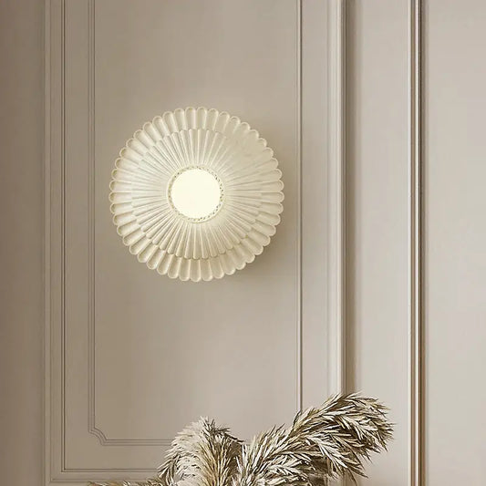 A cream-colored French cream wind sunburst wall lamp with frosted glass diffuser and metallic accents for bedroom decorbites