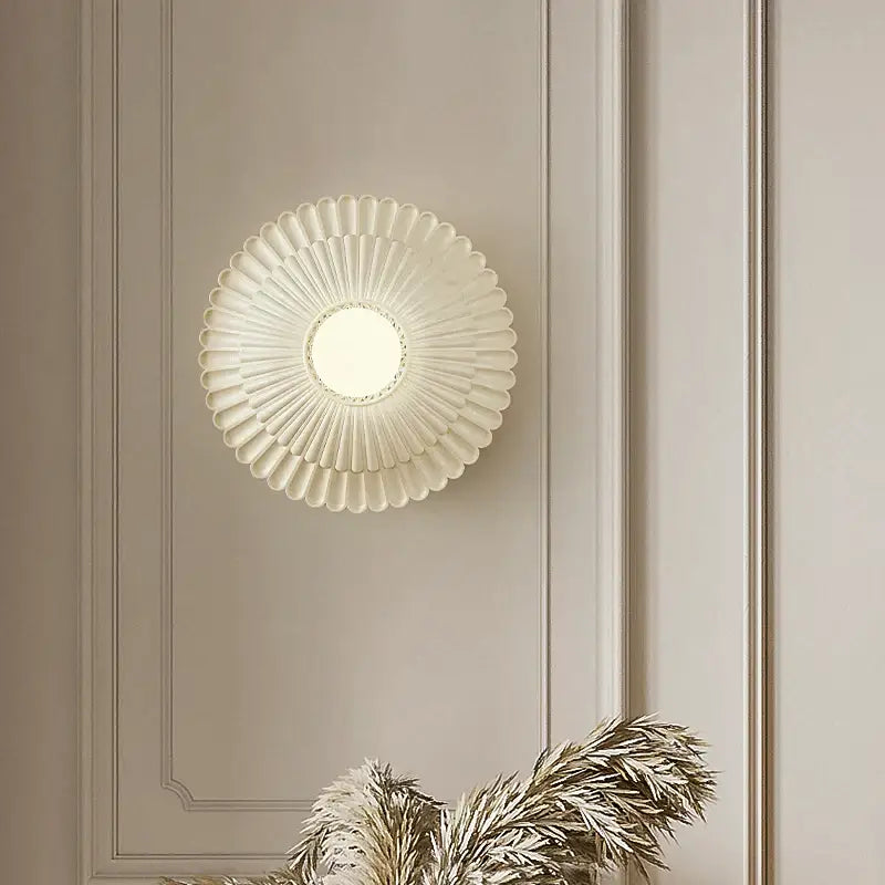 A cream-colored French cream wind sunburst wall lamp with frosted glass diffuser and metallic accents for bedroom decorbites