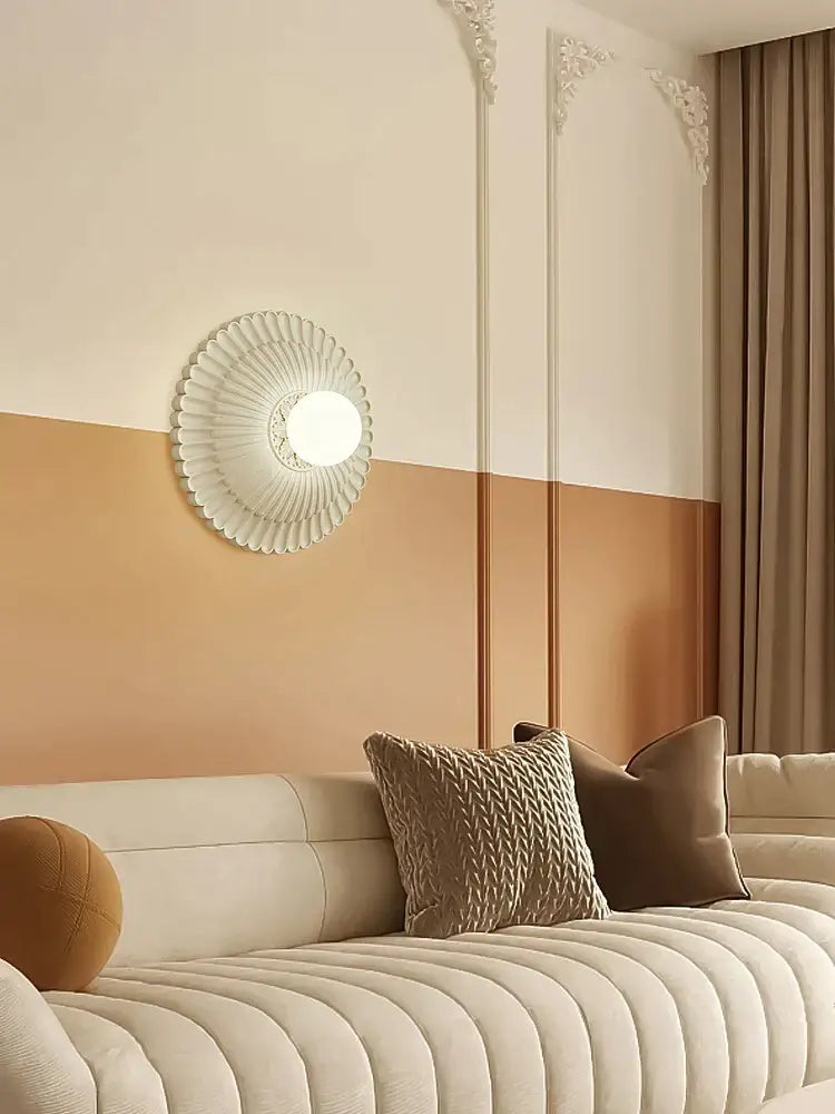 A white circular wall lamp with fluted petals and illuminated bulb in decorbites french cream wind style
