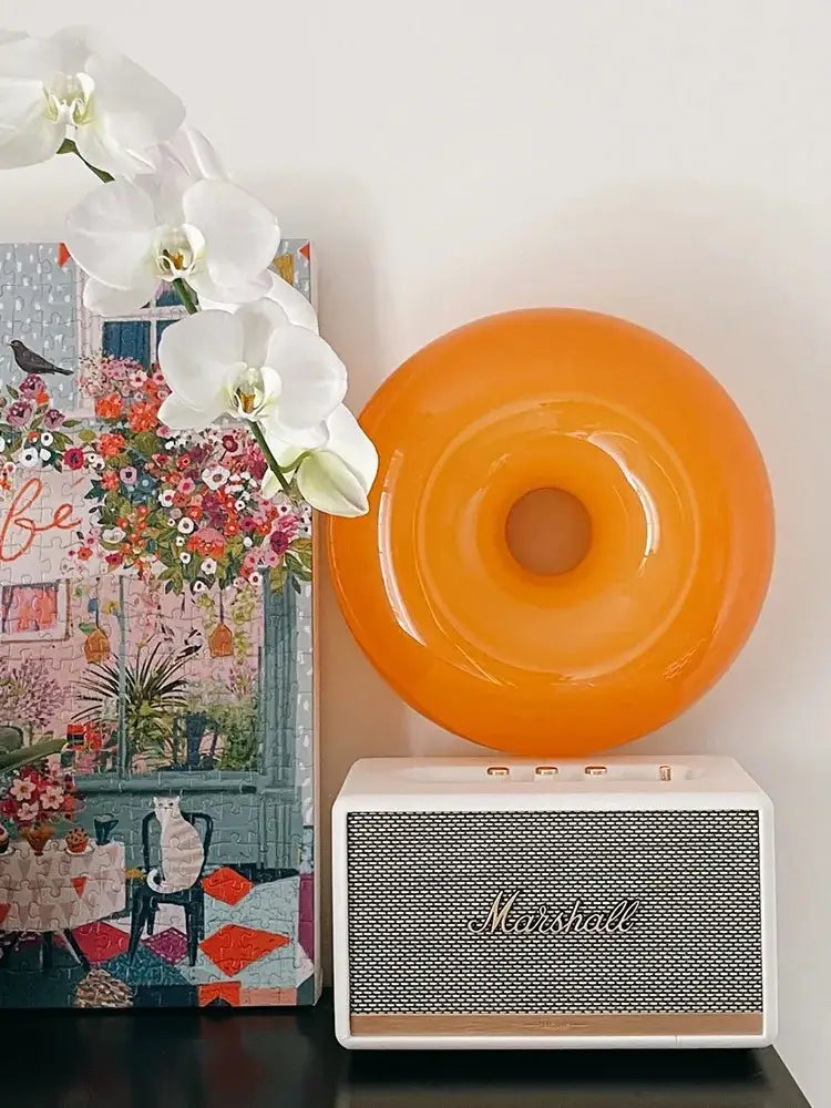Vibrant orange glossy french decorative wall lamp resting on white marshall speaker ideal for bedroom decorbites wall lamps