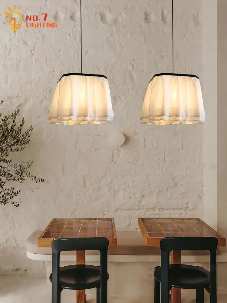 Two cream-colored pleated fabric pendant lights with black trim by decorbites french design for dining room lighting