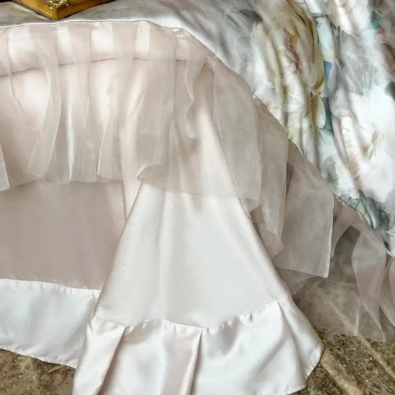 A delicate layered white satin bed skirt with sheer ruffled overlay from decorbites french flowers lace bedding set
