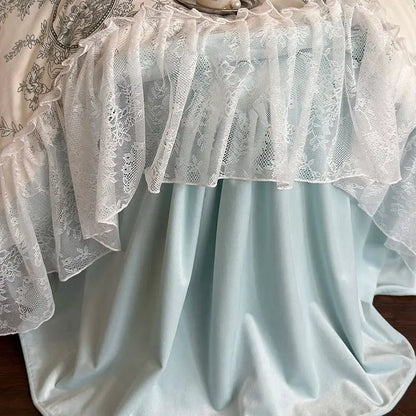 A delicate white lace ruffle drapes elegantly over a light blue satin tablecloth in decorbites french lace bedding set