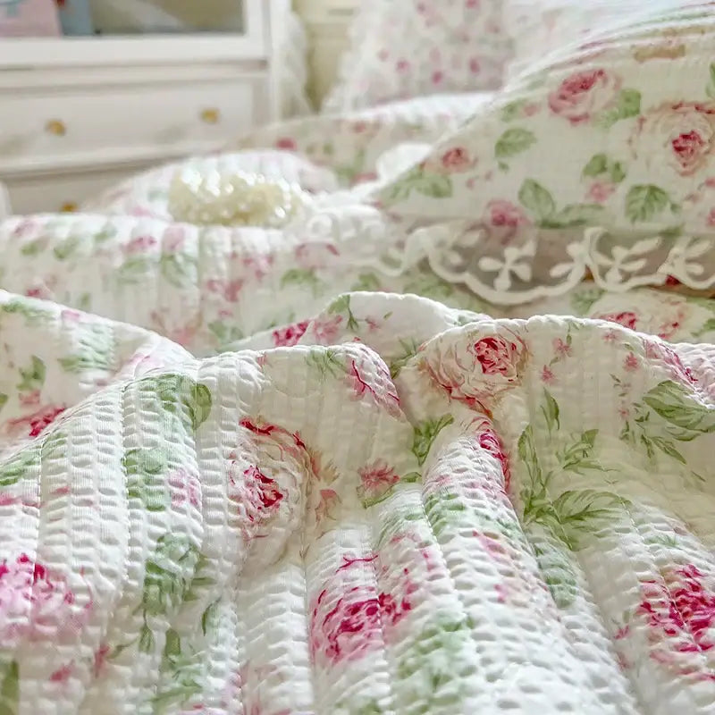 A soft white quilted bedding set with delicate pink and green floral pattern featuring french lace ruffles decorbites french lace