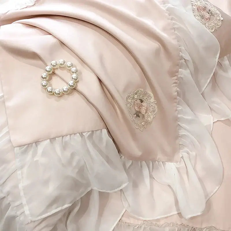 A delicate pearl bracelet on blush pink satin with french lace ruffles in a decorbites french lace bedding set