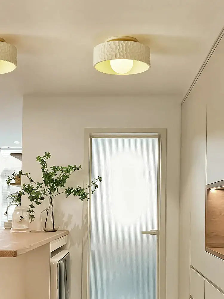 Cream-colored textured ceiling light with gold-toned rim for decorbites french minimalist cream living room decor