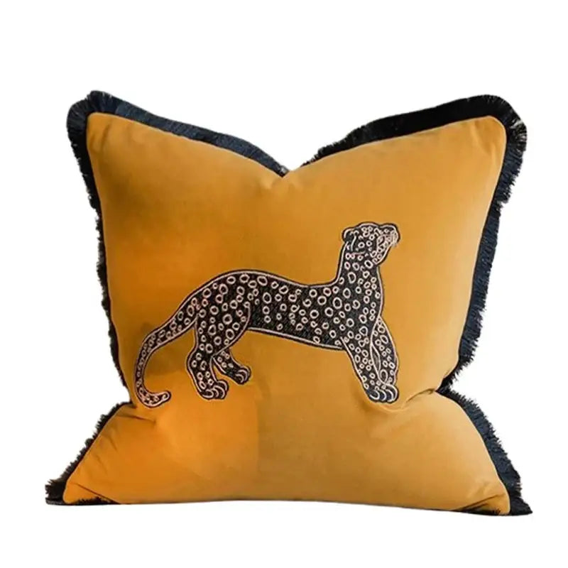 A plush mustard-yellow velvet french night velvet throw pillow featuring an embroidered black leopard with dark blue fringe