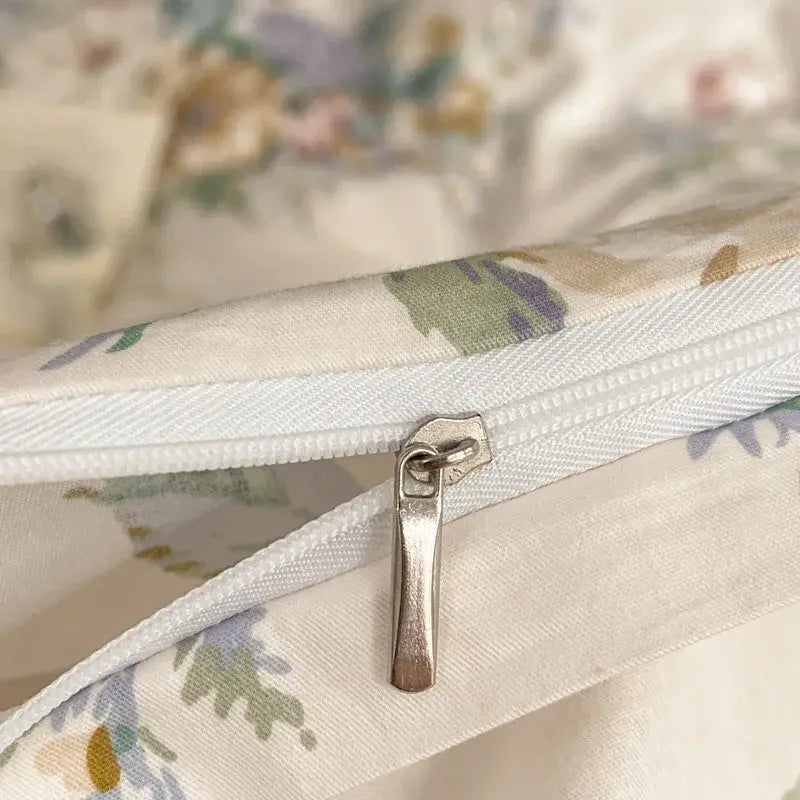 A silver-toned zipper pull on white pastel floral fabric of the decorbites french pastoral princess bedding set