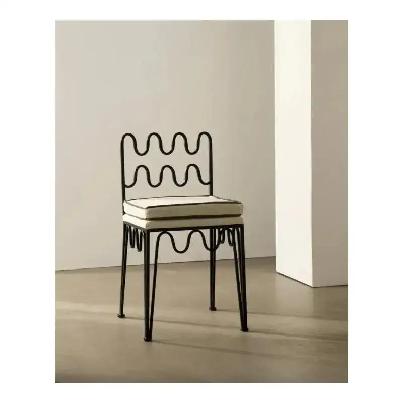 Black wrought iron retro wave dining chair with wavy sculptural back and off-white cushioned seat by decorbites french retro