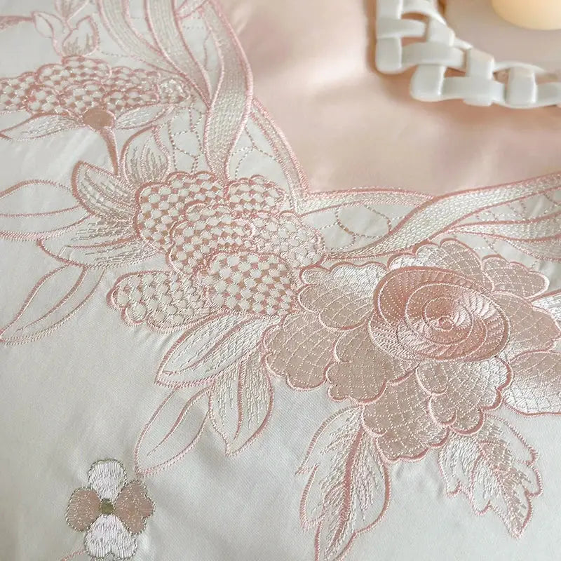 A delicate pink floral embroidery with lace ruffles adorns a soft satin bedding set by decorbites french romantic