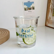 Clear glass tumbler cup with handwritten bon appétit label and lime slices ideal for kitchen juice glass use