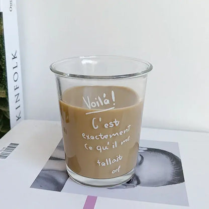 Clear glass tumbler cup with white handwritten french text filled with light brown beverage for kitchen juice use