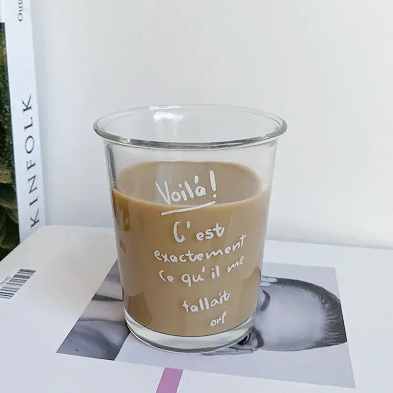Clear glass tumbler cup with white handwritten french text filled with light brown beverage for kitchen juice use