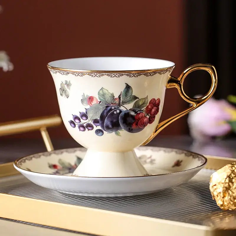 Elegant cream-colored bone china tea cup with gold-trimmed handle and hand-painted fruit motif in decorbites teaware set